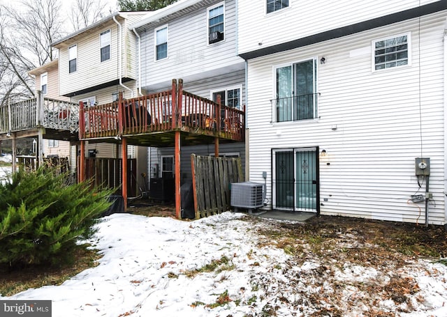 snow covered house with a wooden deck and cooling unit