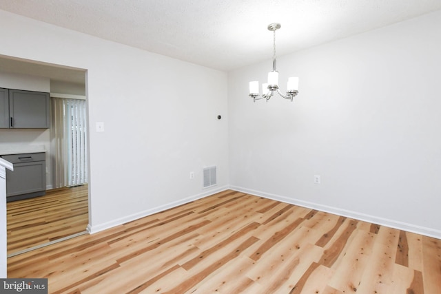 unfurnished dining area with light hardwood / wood-style flooring and a notable chandelier