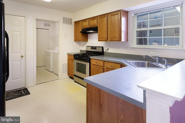 kitchen featuring washer and dryer, sink, kitchen peninsula, and stainless steel gas range oven