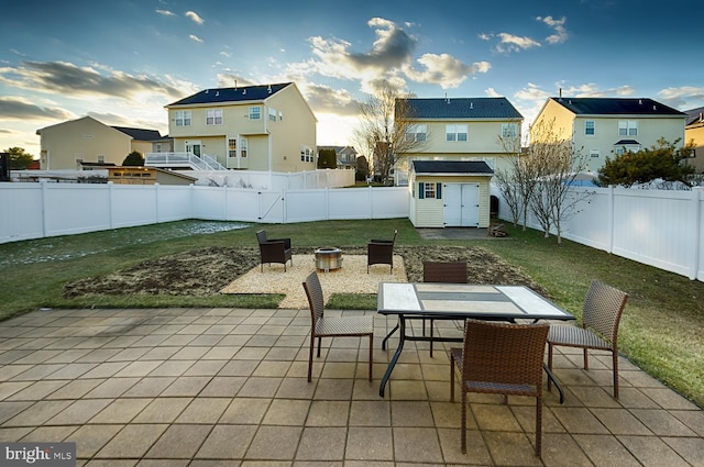 patio terrace at dusk featuring a lawn and a storage unit