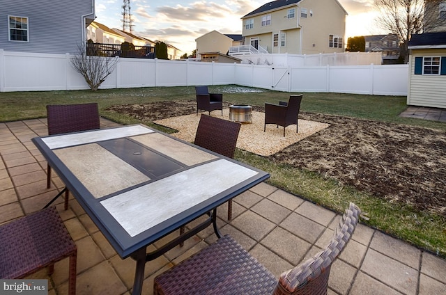 patio terrace at dusk featuring a yard