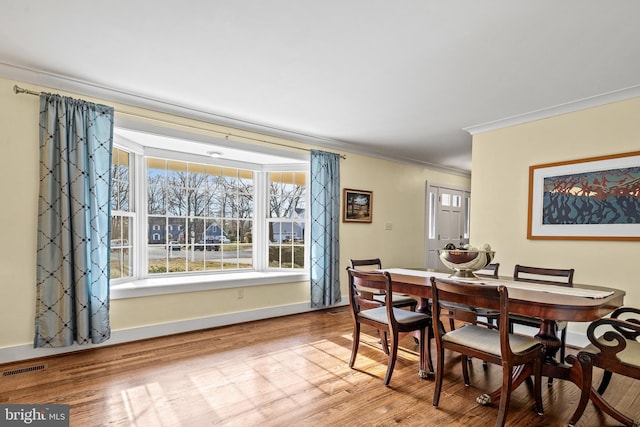 dining area featuring ornamental molding and light hardwood / wood-style flooring