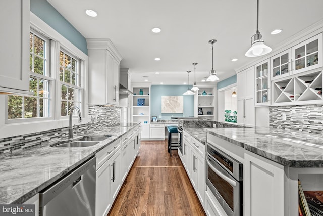 kitchen with appliances with stainless steel finishes, backsplash, pendant lighting, white cabinets, and sink