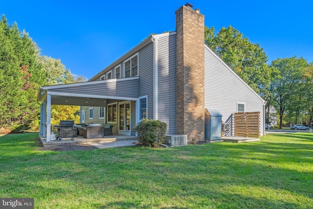 rear view of property with central air condition unit, a lawn, and a patio