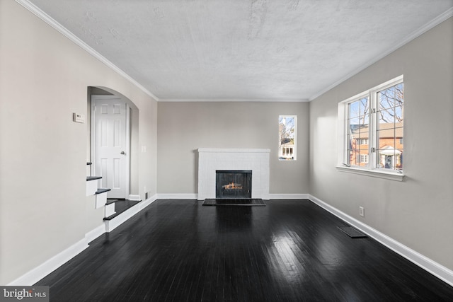 unfurnished living room featuring a textured ceiling, a brick fireplace, ornamental molding, and hardwood / wood-style flooring