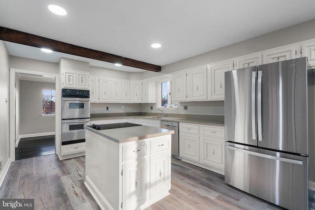 kitchen featuring white cabinets, light wood-type flooring, appliances with stainless steel finishes, and a center island