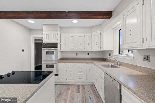 kitchen featuring white cabinetry, stainless steel appliances, light hardwood / wood-style floors, sink, and beam ceiling