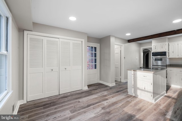 kitchen with hardwood / wood-style flooring, white cabinets, beam ceiling, and a kitchen island