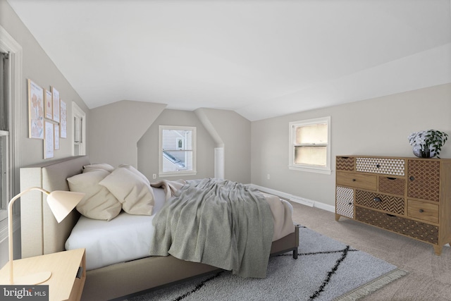 carpeted bedroom featuring lofted ceiling and multiple windows