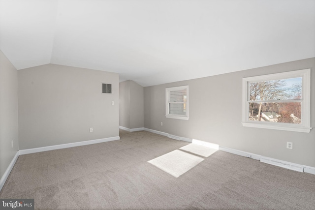 carpeted empty room with lofted ceiling