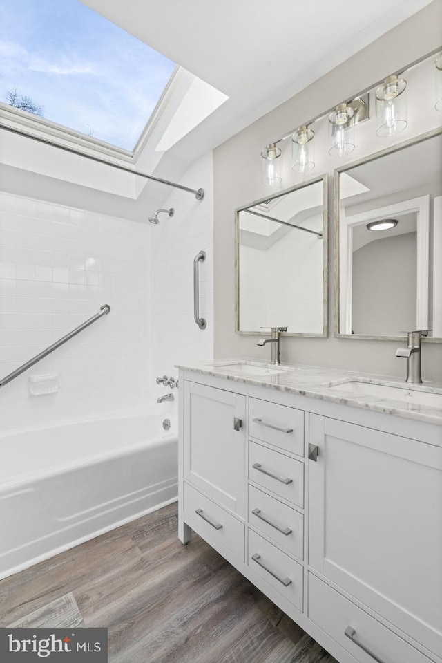 bathroom with a skylight, tiled shower / bath combo, hardwood / wood-style flooring, and vanity