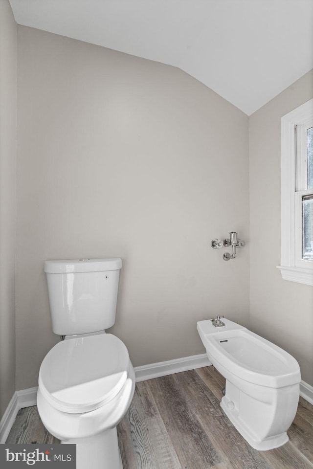 bathroom with vaulted ceiling, toilet, wood-type flooring, and a bidet