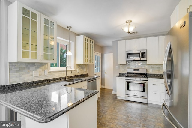 kitchen featuring sink, hanging light fixtures, kitchen peninsula, stainless steel appliances, and white cabinets