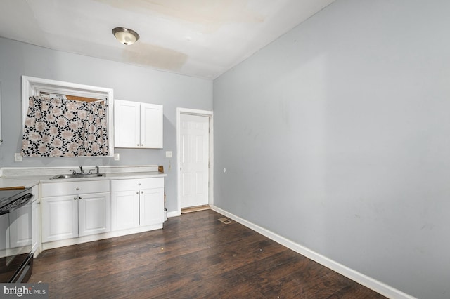 kitchen with black electric range oven, sink, white cabinets, and dark hardwood / wood-style floors