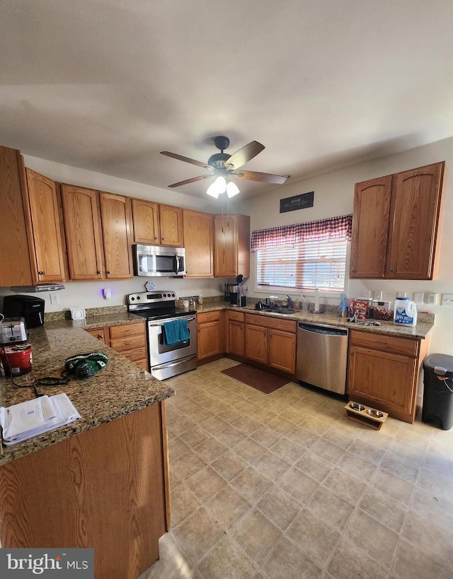 kitchen with ceiling fan, sink, stainless steel appliances, and dark stone counters