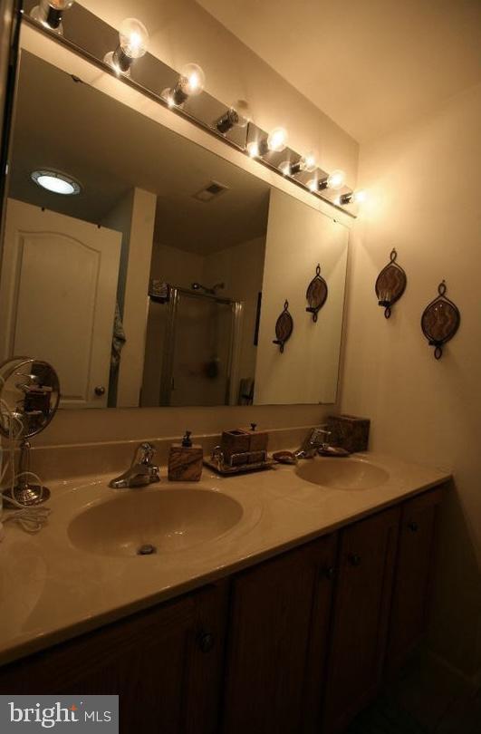 bathroom featuring a shower with shower door and vanity