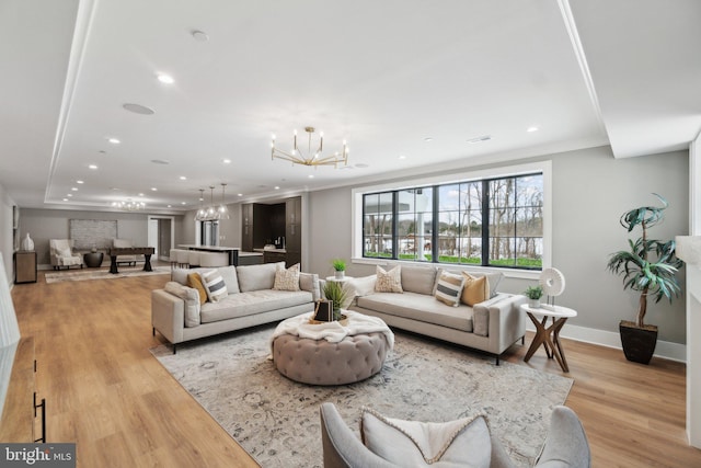 living room with a notable chandelier, light hardwood / wood-style floors, and crown molding