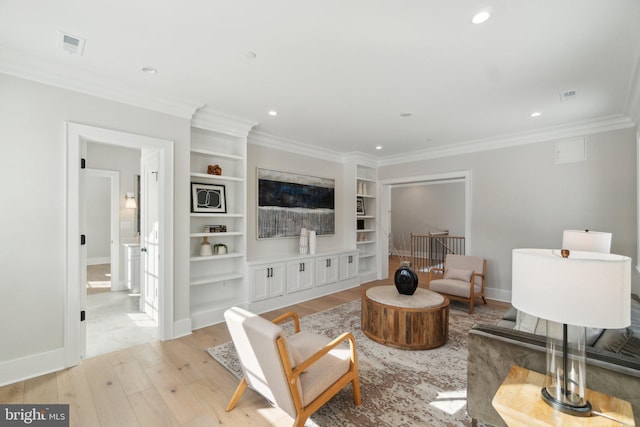 living room with light hardwood / wood-style floors, ornamental molding, and built in shelves