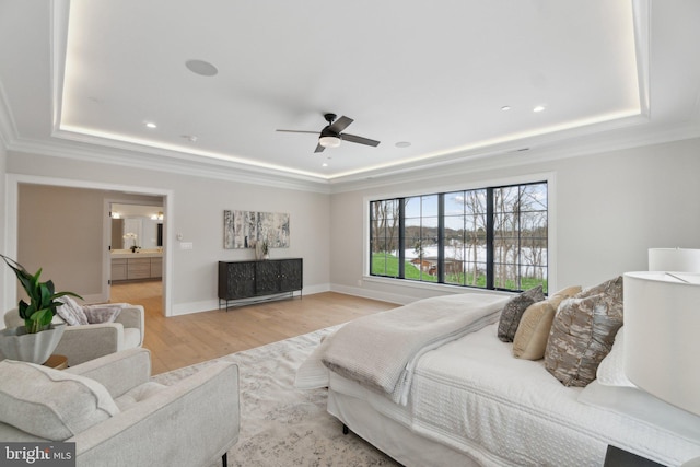 bedroom with ceiling fan, light hardwood / wood-style floors, ensuite bathroom, and a raised ceiling