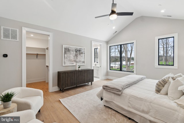 bedroom with vaulted ceiling, a spacious closet, ceiling fan, light wood-type flooring, and a closet