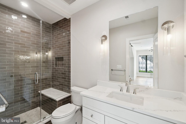 bathroom with a shower with door, vanity, and toilet