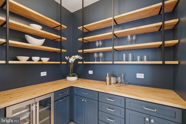 bar featuring wooden counters, blue cabinets, and wine cooler