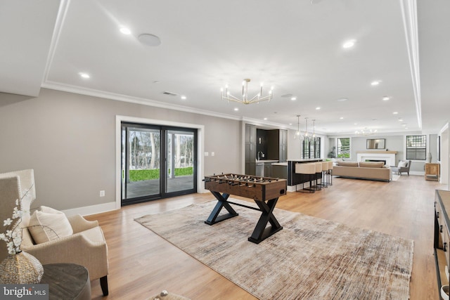 rec room with light hardwood / wood-style flooring, a chandelier, crown molding, and plenty of natural light