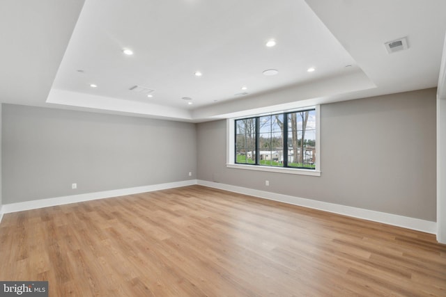 spare room featuring light hardwood / wood-style floors and a raised ceiling