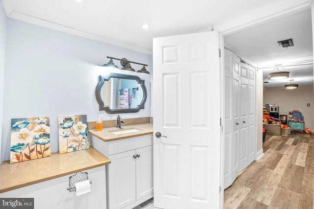 bathroom featuring ornamental molding, vanity, and wood-type flooring