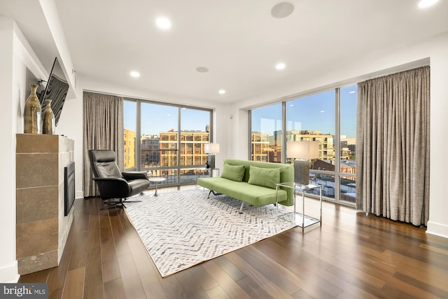 sitting room featuring floor to ceiling windows, a city view, plenty of natural light, and dark wood-style flooring