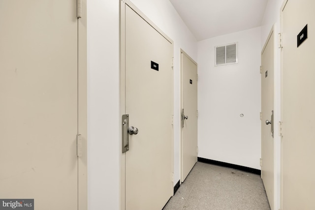 hallway featuring baseboards, visible vents, and light floors