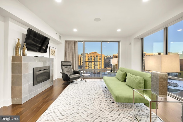 living room with a tile fireplace, expansive windows, and dark hardwood / wood-style flooring