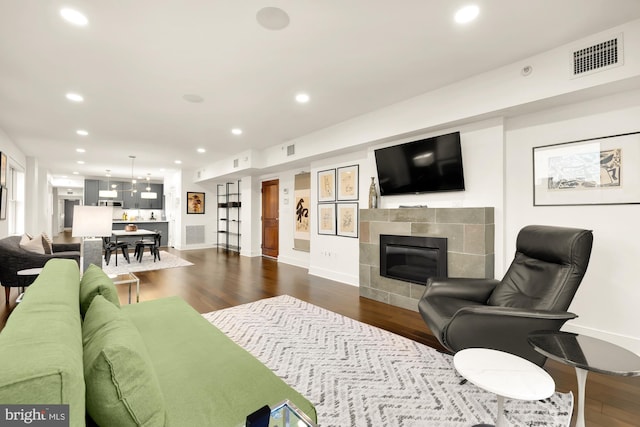 living area featuring recessed lighting, visible vents, dark wood finished floors, and a tiled fireplace