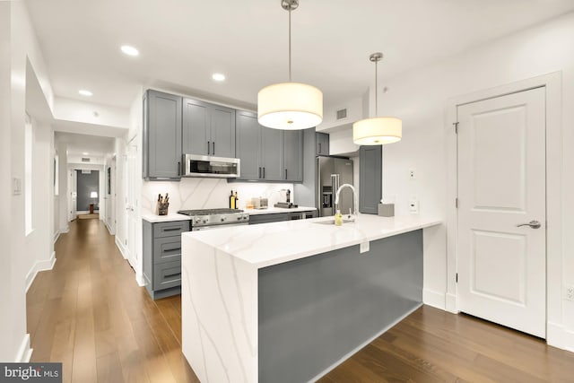 kitchen with high end appliances, decorative light fixtures, a peninsula, and gray cabinetry