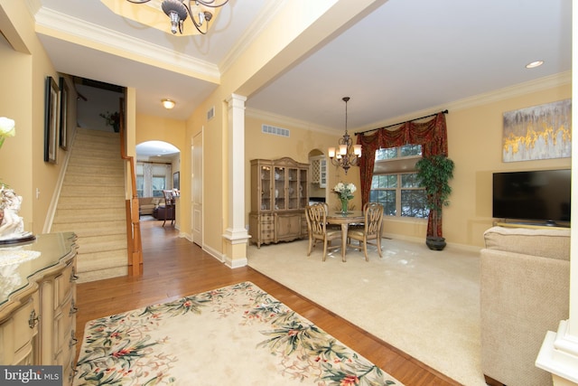 dining space featuring ornamental molding, hardwood / wood-style floors, an inviting chandelier, and ornate columns