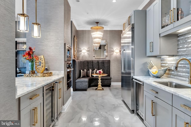 kitchen with pendant lighting, sink, appliances with stainless steel finishes, gray cabinetry, and light stone counters