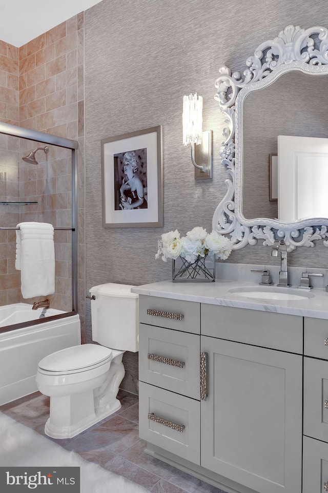 full bathroom with toilet, vanity, and bath / shower combo with glass door