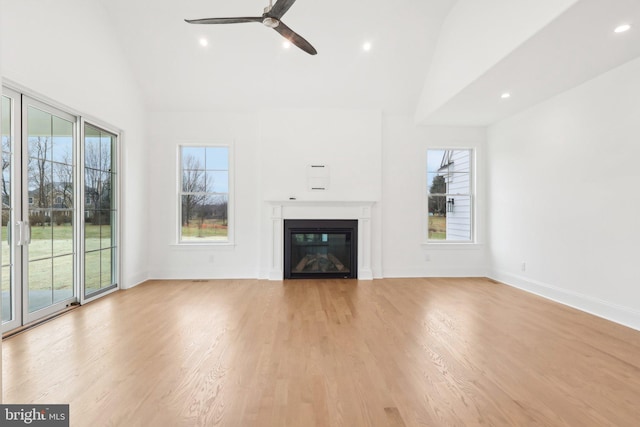 unfurnished living room with light wood-type flooring, ceiling fan, and plenty of natural light