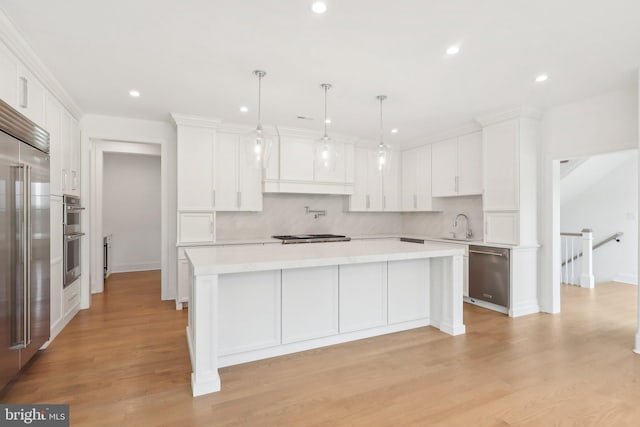 kitchen featuring a kitchen island, white cabinets, appliances with stainless steel finishes, and light hardwood / wood-style flooring