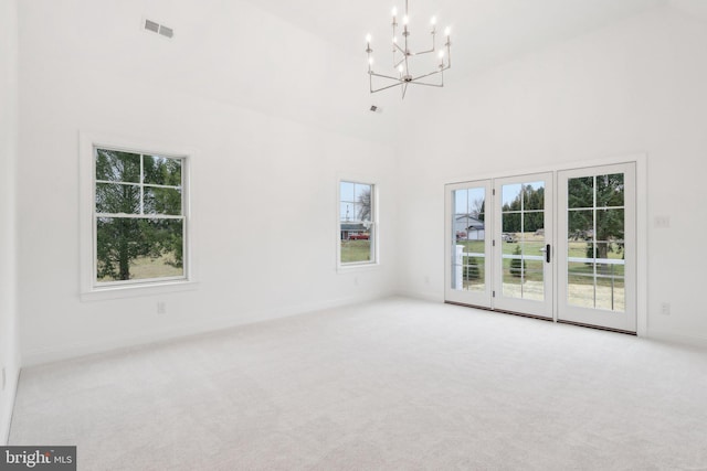 unfurnished living room with a high ceiling, an inviting chandelier, and light carpet