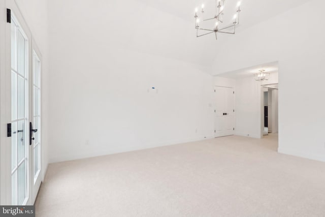 carpeted empty room with high vaulted ceiling and an inviting chandelier