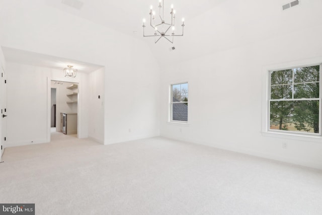 carpeted spare room with high vaulted ceiling and an inviting chandelier