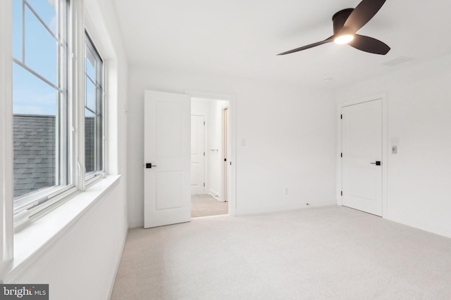 spare room with ceiling fan and light colored carpet