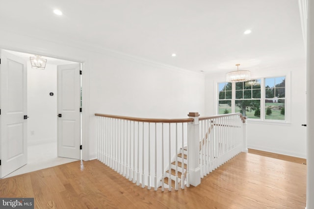 hallway featuring a notable chandelier, crown molding, and light hardwood / wood-style floors