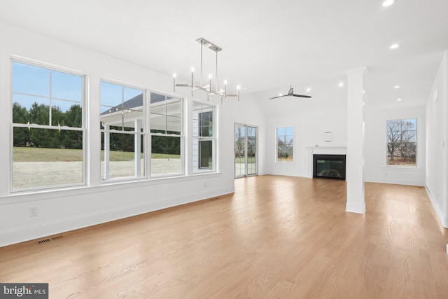 unfurnished living room featuring a healthy amount of sunlight, light wood-type flooring, and ceiling fan with notable chandelier