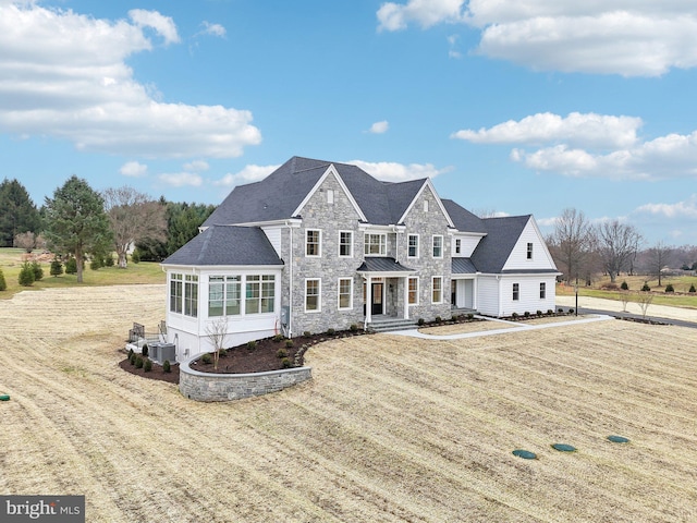 view of front of house featuring a front lawn, cooling unit, and a sunroom