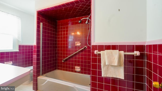 bathroom with tile walls and tiled shower / bath combo