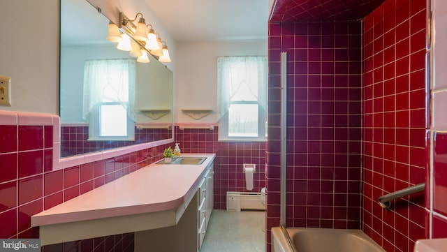 bathroom with a baseboard radiator, tile walls, and a healthy amount of sunlight