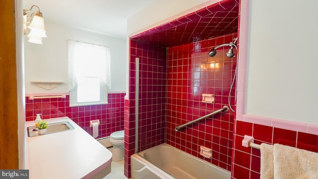 full bathroom featuring toilet, tile walls, tiled shower / bath combo, a baseboard radiator, and vanity