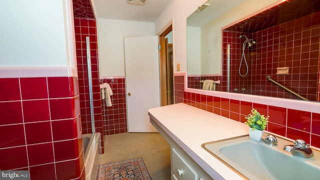 bathroom with tile walls, enclosed tub / shower combo, and vanity